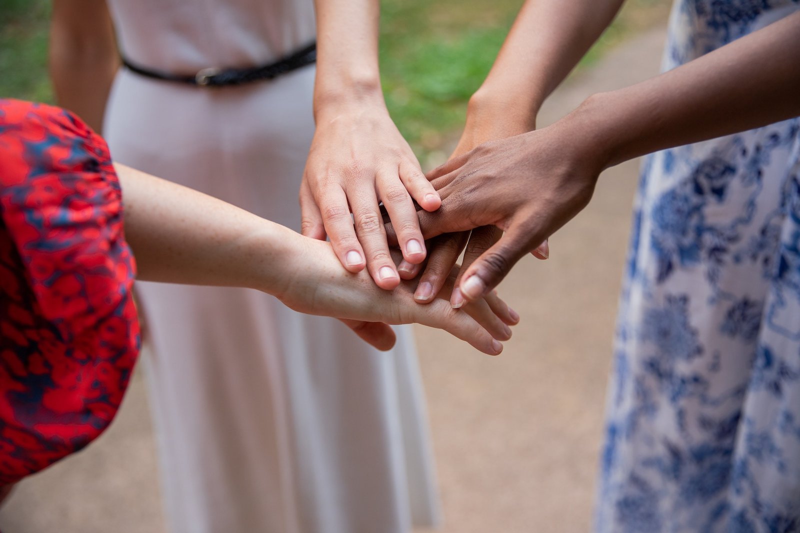Multi-ethnic youth group at park joins hands to manifest togetherness. Friendship concept