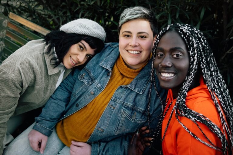 Multiethnic women smiling watching the camera sitting on a bench