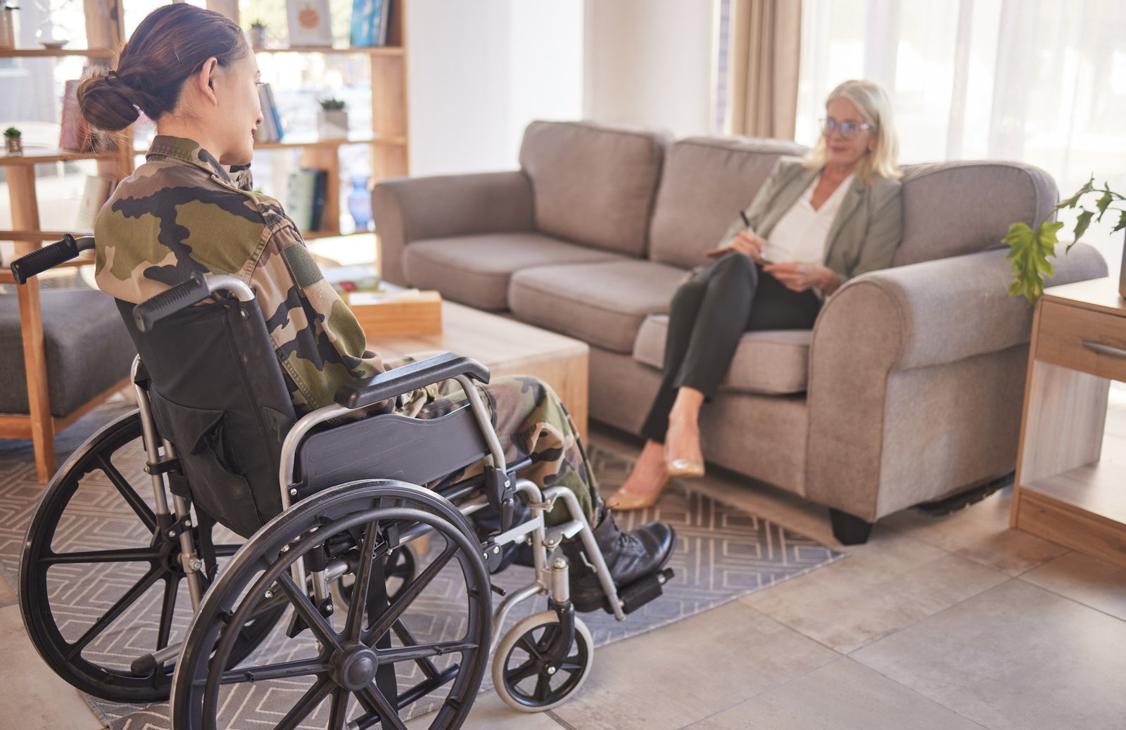 Soldier woman, wheelchair and therapist in talk, rehabilitation or support for war trauma. Psycholo