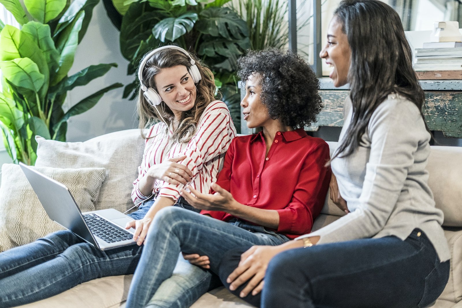 Three happy women with laptop sitting on couch