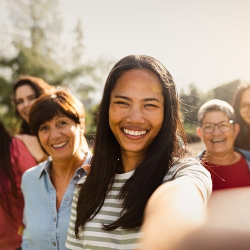 Happy multigenerational group of women having fun taking selfie with smartphone camera in a park
