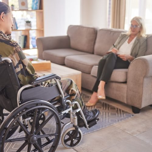 Soldier woman, wheelchair and therapist in talk, rehabilitation or support for war trauma. Psycholo