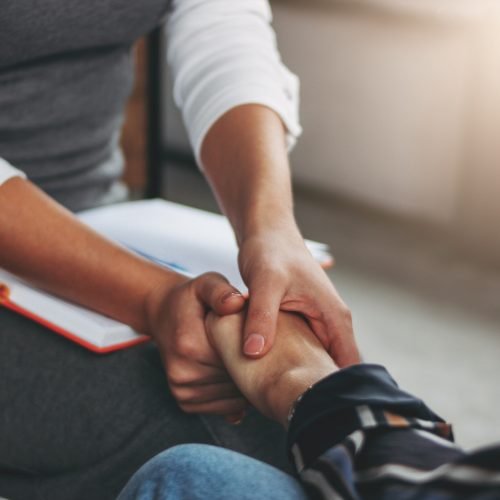 Woman support and help concept. Women hold each other's hands sitting in loft office